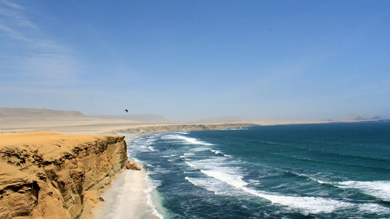 Littoral désertique de la côte pacifique péruvienne avec dunes de sable ocre plongeant vers l'océan